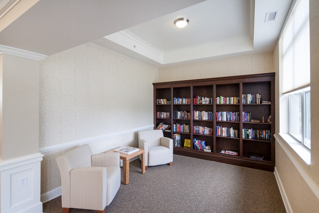 a library with chairs and a table and a book shelf