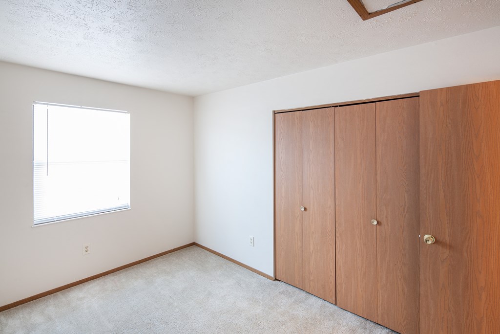 an empty bedroom with two closets and a window