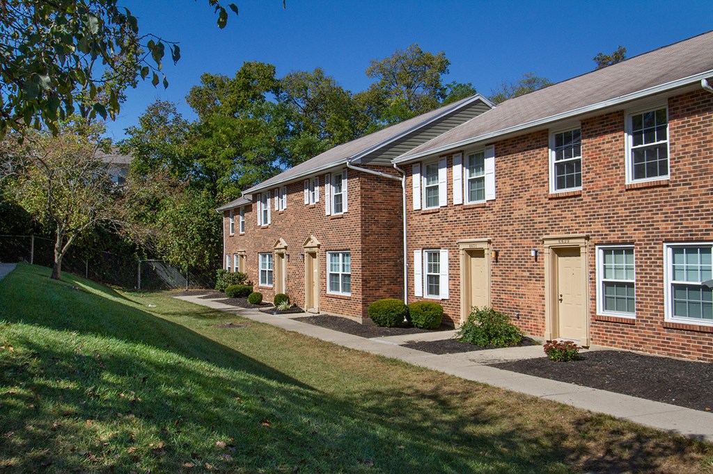 a brick apartment building with a sidewalk and grass