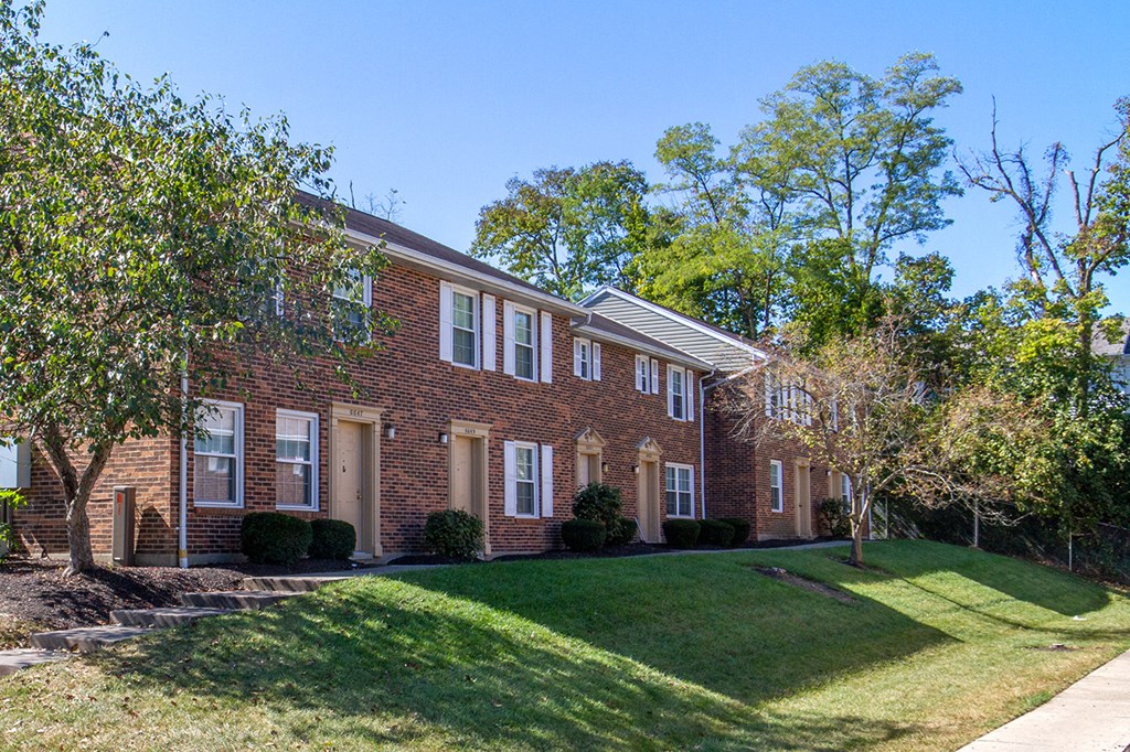 a brick house with a lawn and trees