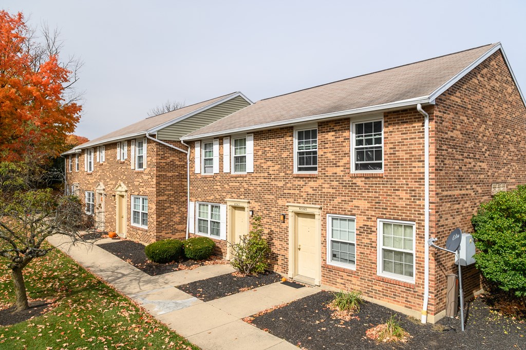 a brick house with yellow doors and a sidewalk