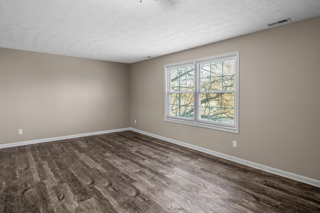 an empty living room with wood floors and a window