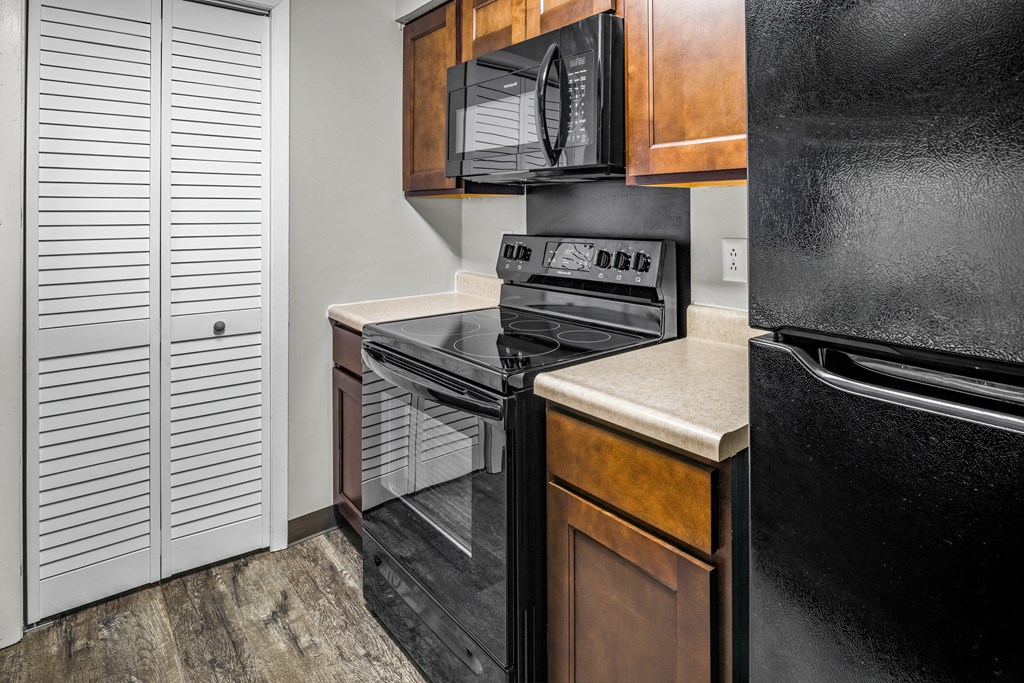 a kitchen with black appliances and wooden cabinets and a black refrigerator