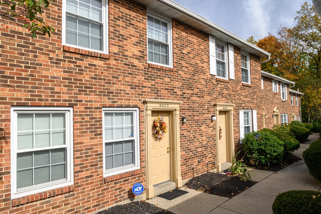 a brick apartment building with yellow doors and a wreath on the door