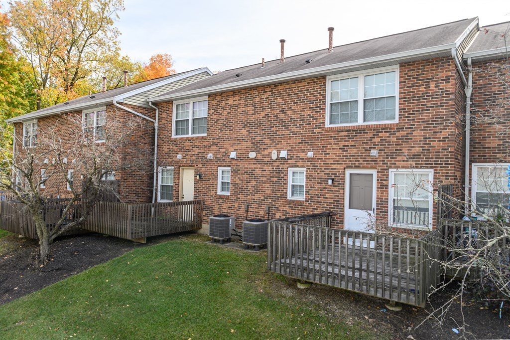 the front of a brick house with a yard and a wooden fence