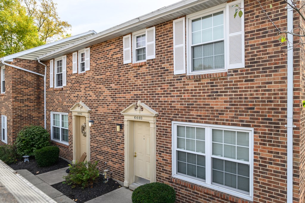 the front of a brick house with white windows and doors