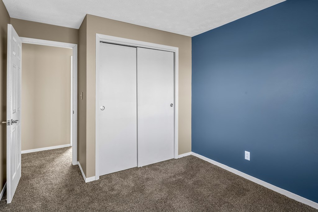 an empty room with a blue wall and a white closet