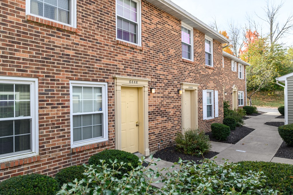 a brick apartment building with yellow doors and a sidewalk
