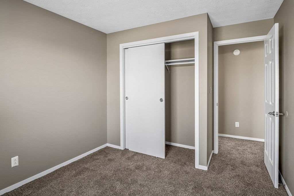 an empty bedroom with a closet and a door open