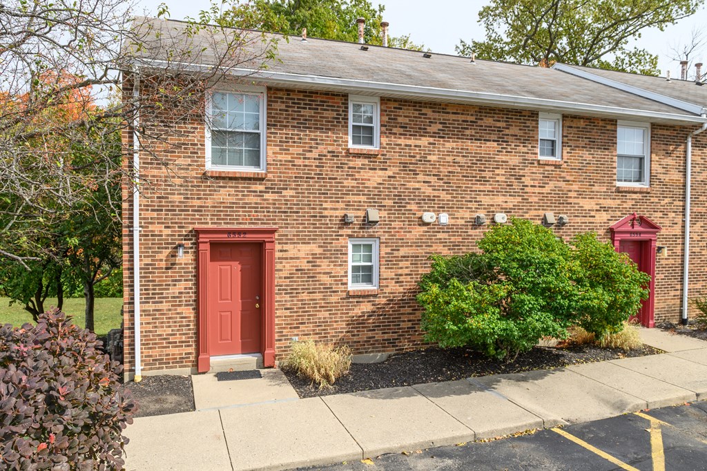 the front of a brick house with a red door
