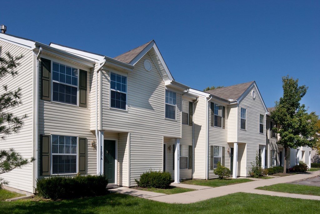 a row of town houses with white siding and a sidewalk