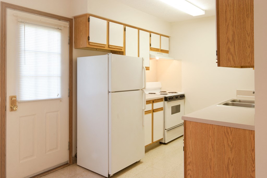 a kitchen with white appliances and wooden cabinets and a white door