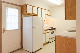 a kitchen with white appliances and wooden cabinets and a white door