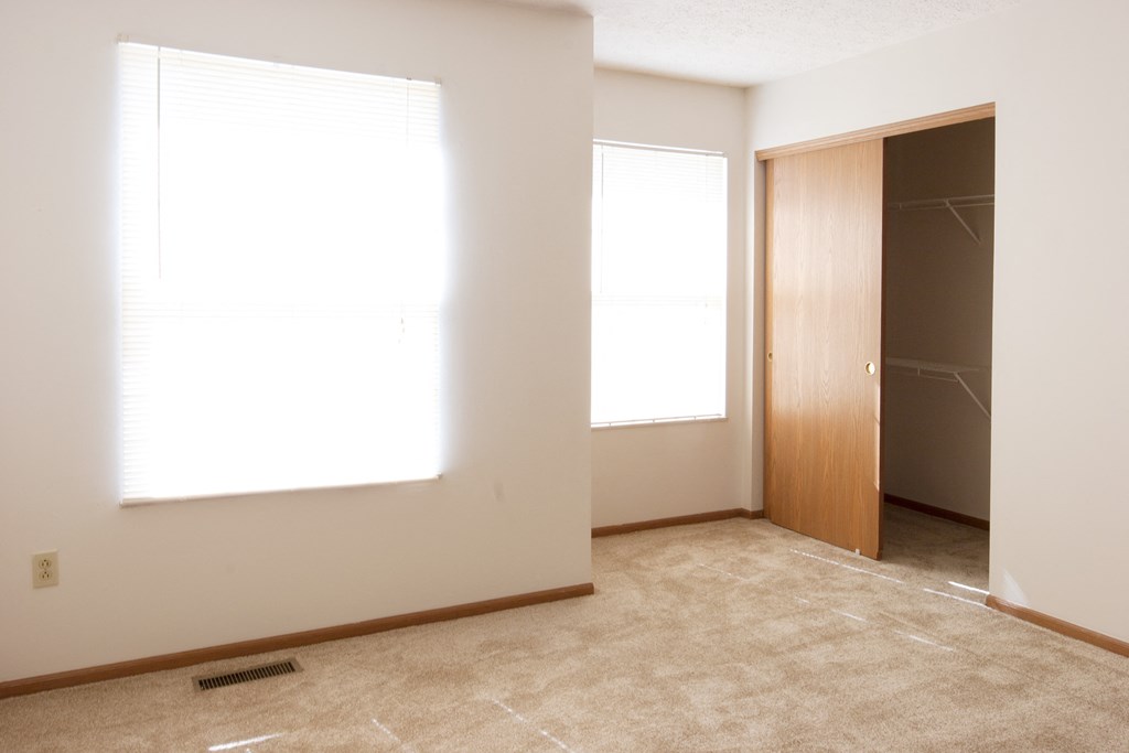 an empty room with two windows and a closet
