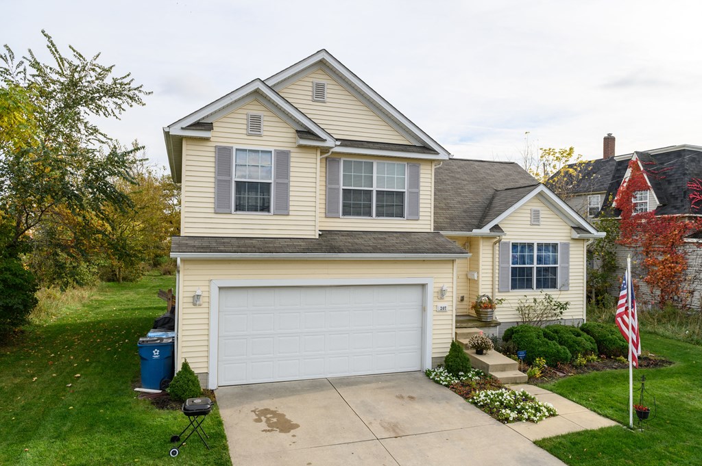 a yellow house with a white garage door on a driveway
