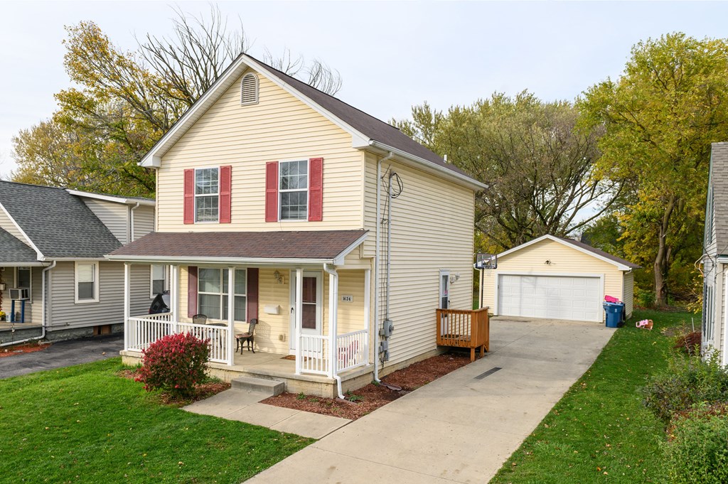 a small yellow house with red shutters and a driveway
