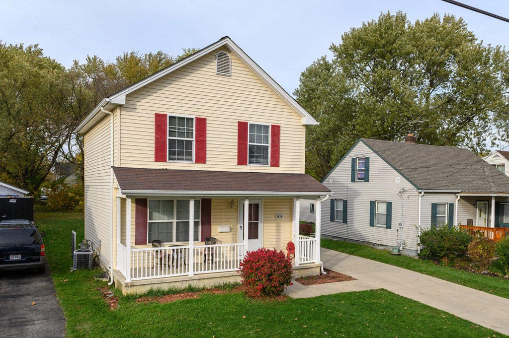 a yellow house with red shutters and a white house on a street