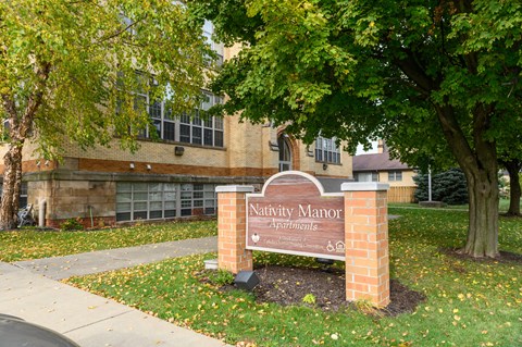 a sign in front of a building with a tree