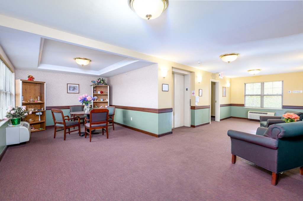 a community room with couches chairs and a table in the corner