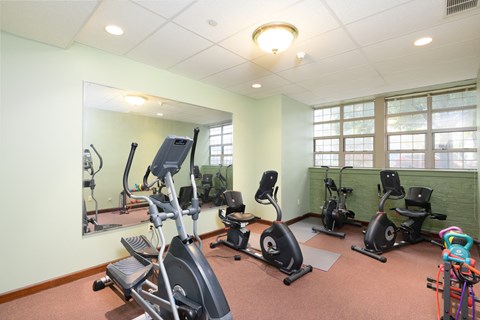 the gym has plenty of exercise equipment and a large mirror