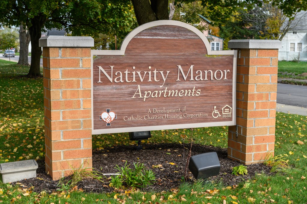 a sign for natty manor apartments in front of a brick fence