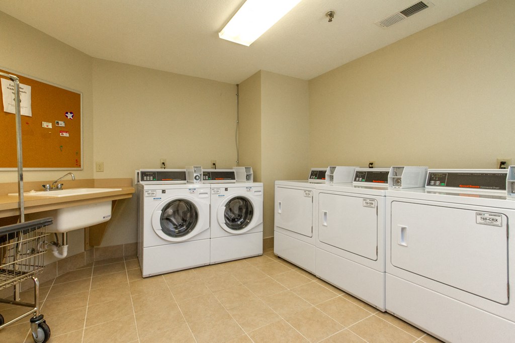 washes and dryers in the laundry room of an apartment building