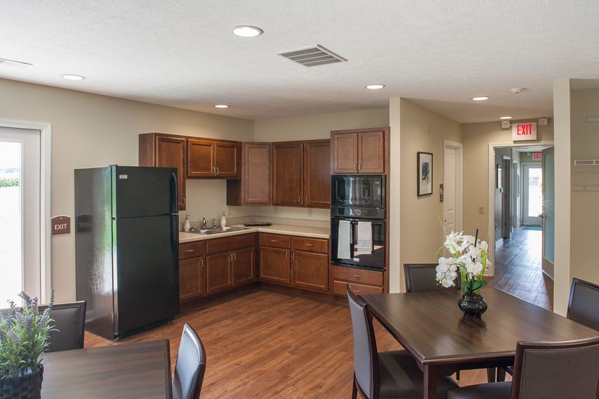 a kitchen with black appliances and a wooden table and chairs
