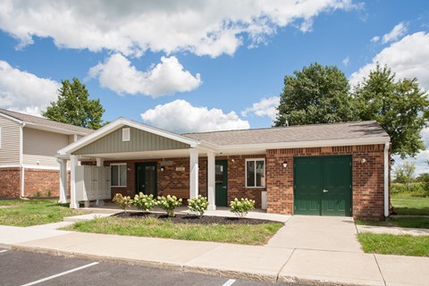 a brick house with green doors and a sidewalk