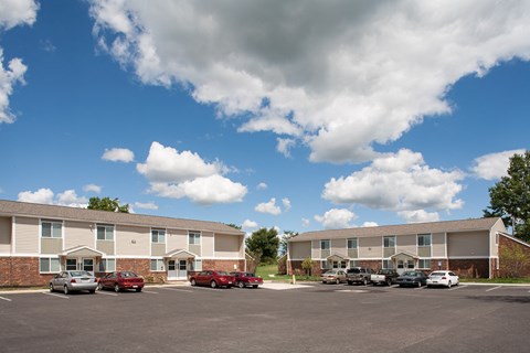 an apartment building with cars parked in a parking lot
