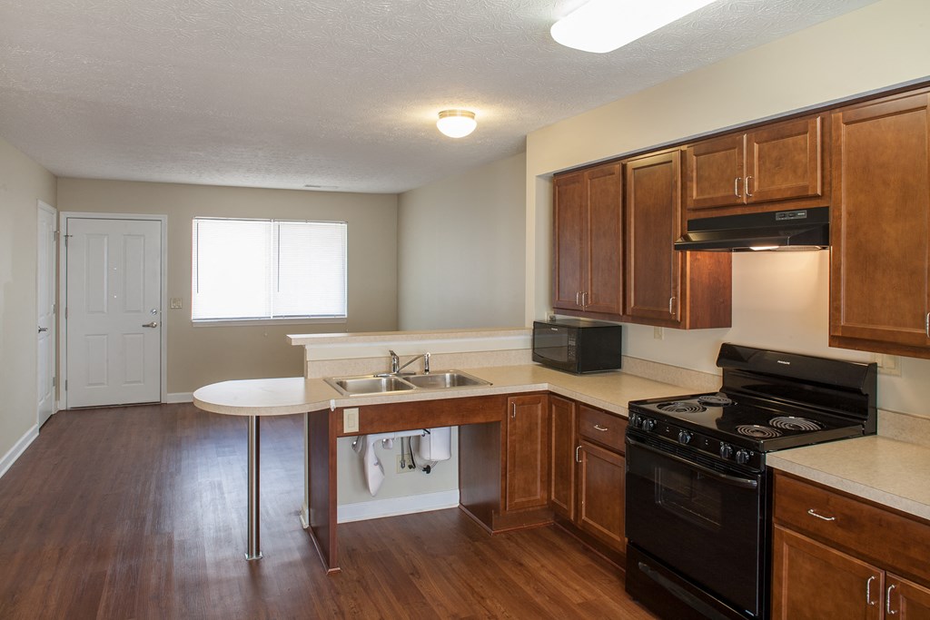 an empty kitchen with wood flooring and wooden cabinets