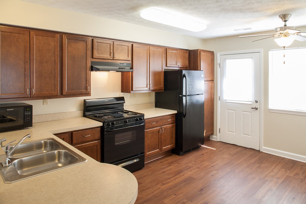 an empty kitchen with wood flooring and black appliances
