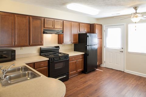 an empty kitchen with wood flooring and black appliances