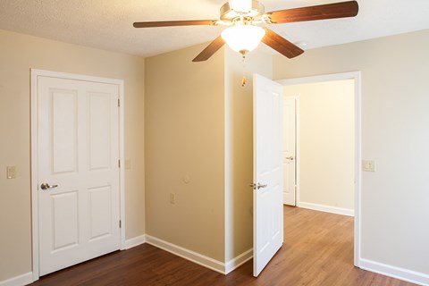 an empty living room with a ceiling fan and a closet