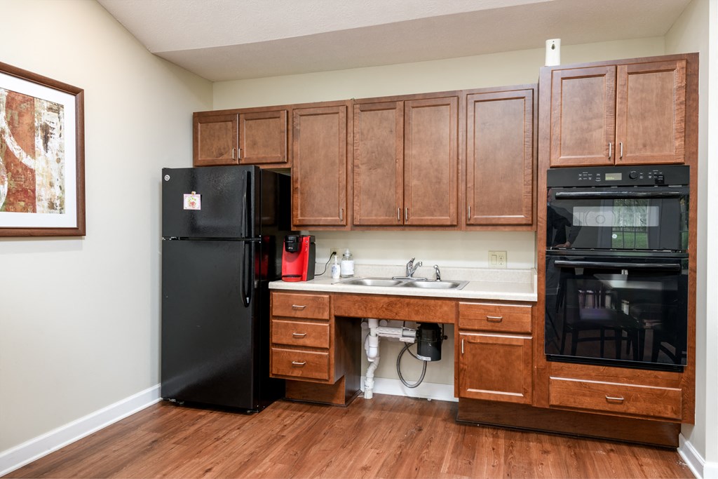 a kitchen with wooden cabinets and a sink and a black refrigerator