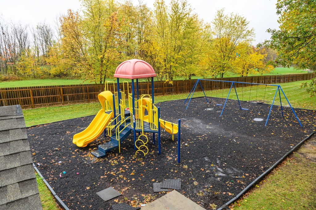 a playground with a swing set and slides in a park