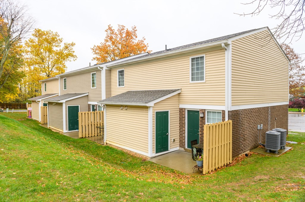 the back of a house with a yard and a wooden fence