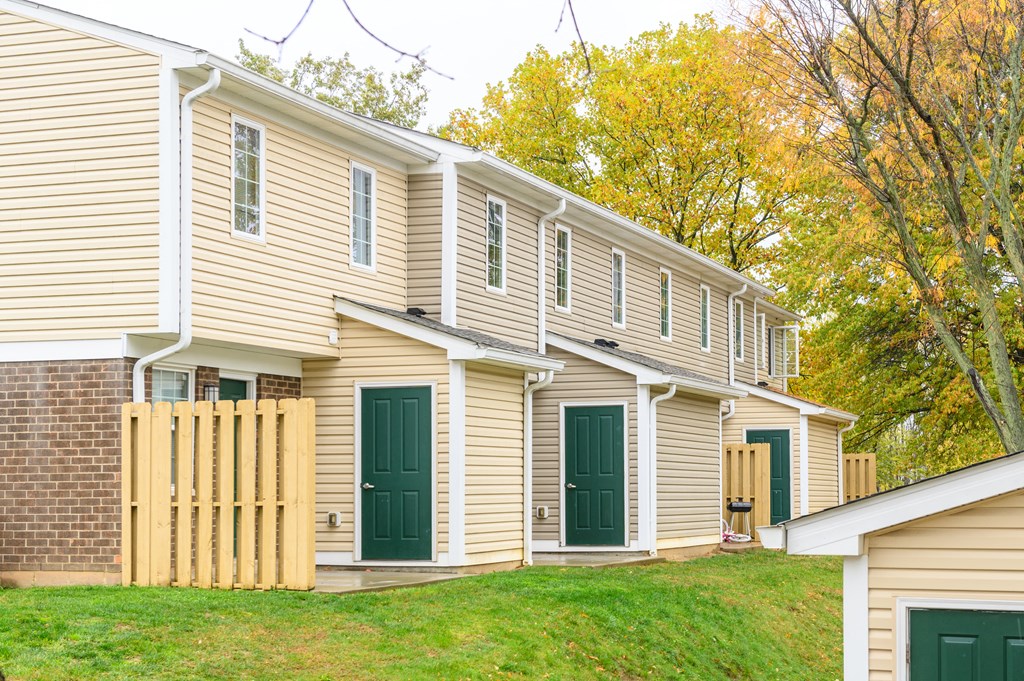 the side of a house with green doors and a lawn