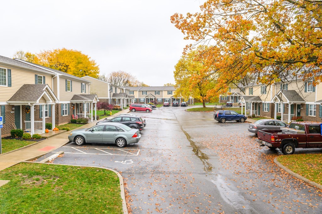 a rainy street with cars parked in front of houses