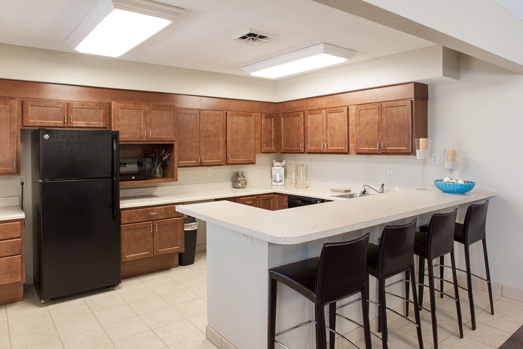 a kitchen with a large island with bar stools and a black refrigerator