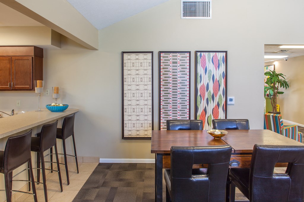 a dining area with a wooden table and chairs and a kitchen with a bar area
