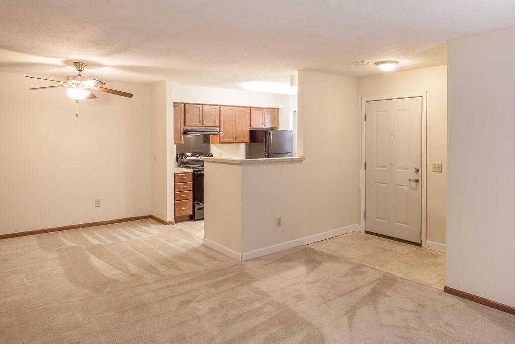 an empty living room and kitchen with a ceiling fan