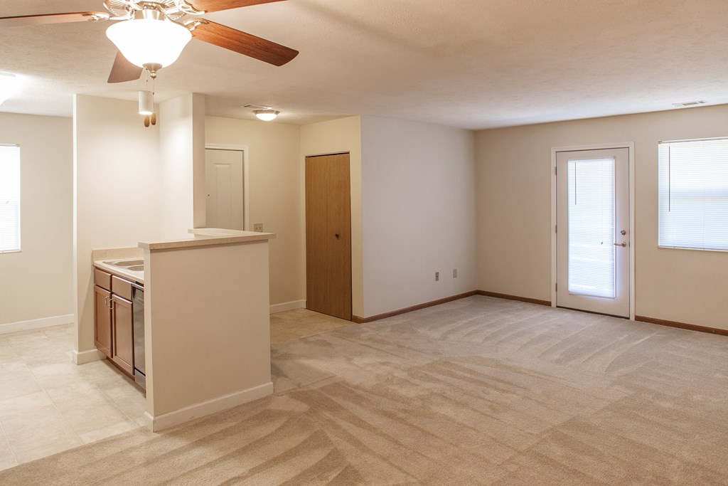 an empty living room and kitchen with a ceiling fan