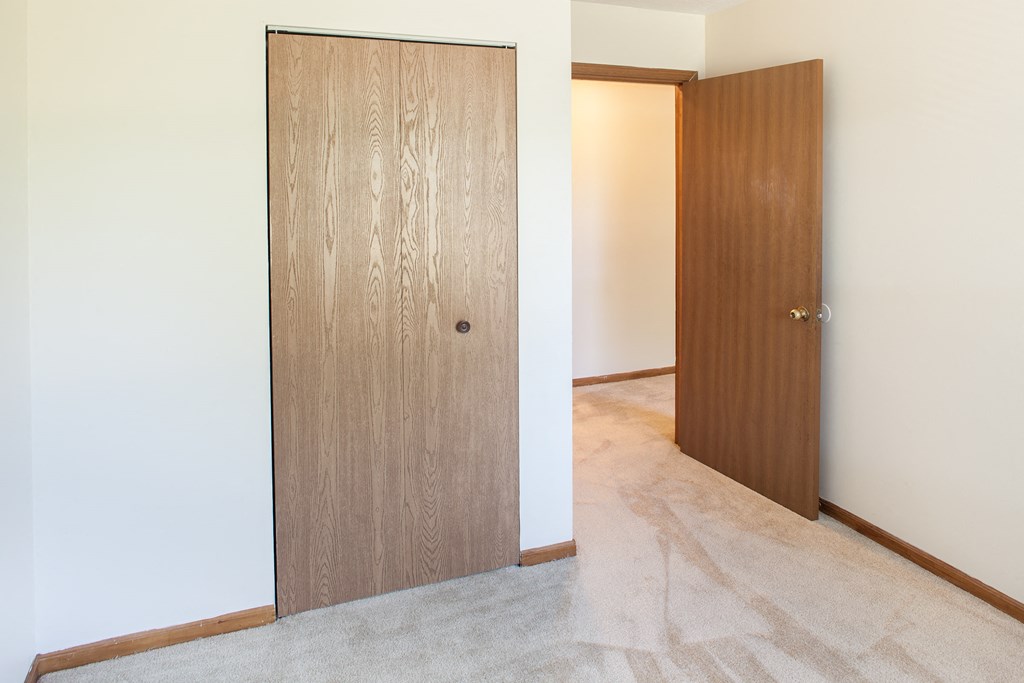 a wooden door in a room next to a white wall and a carpeted floor