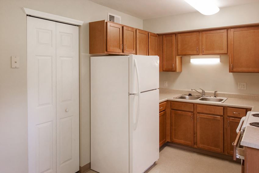 a kitchen with a white refrigerator and wooden cabinets
