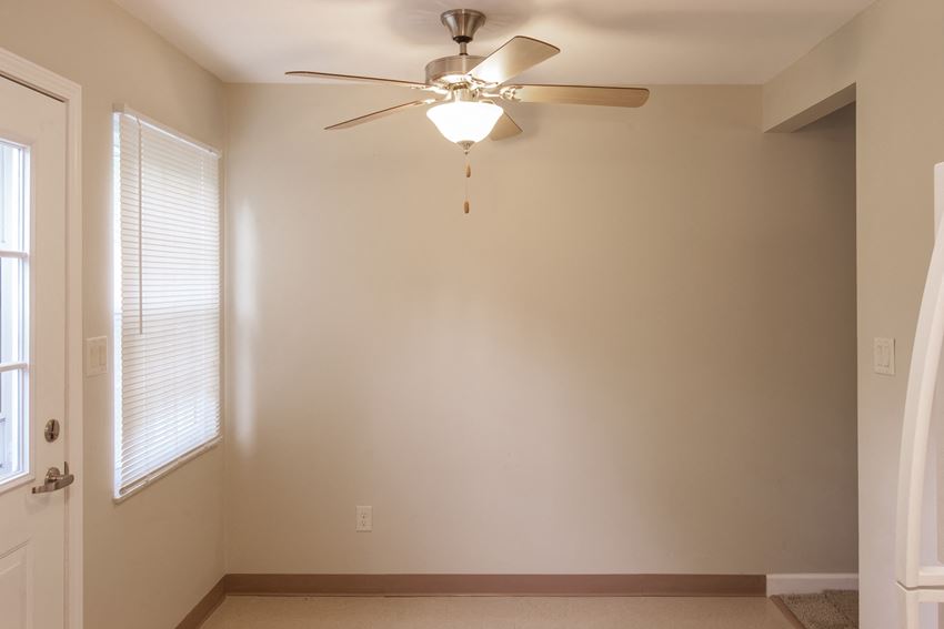 an empty living room with a ceiling fan and a window