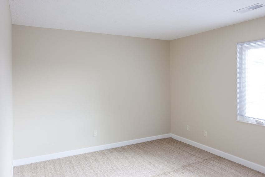 an empty room with beige walls and a window