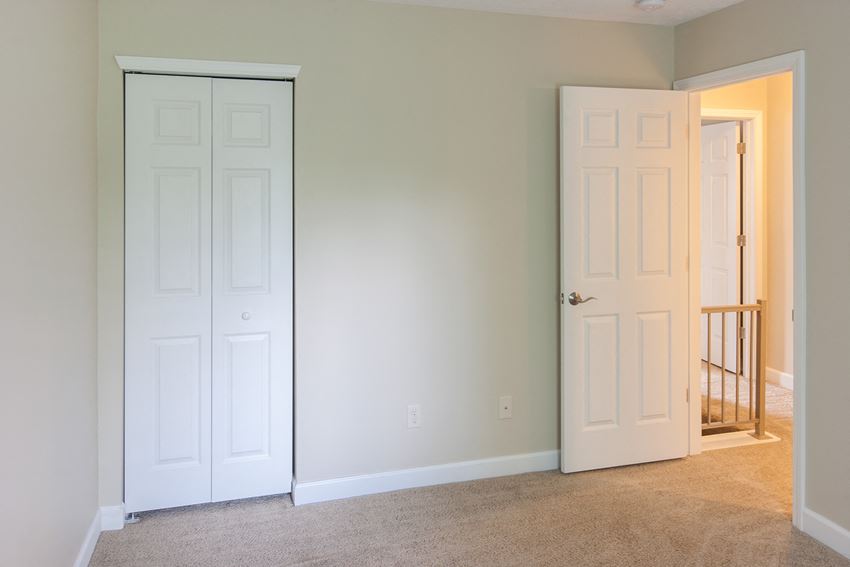 an empty room with two white doors and a door to a hallway