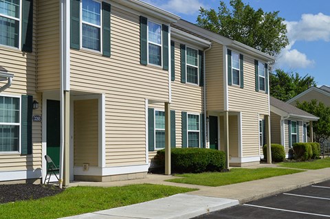 an apartment building with tan siding and green grass