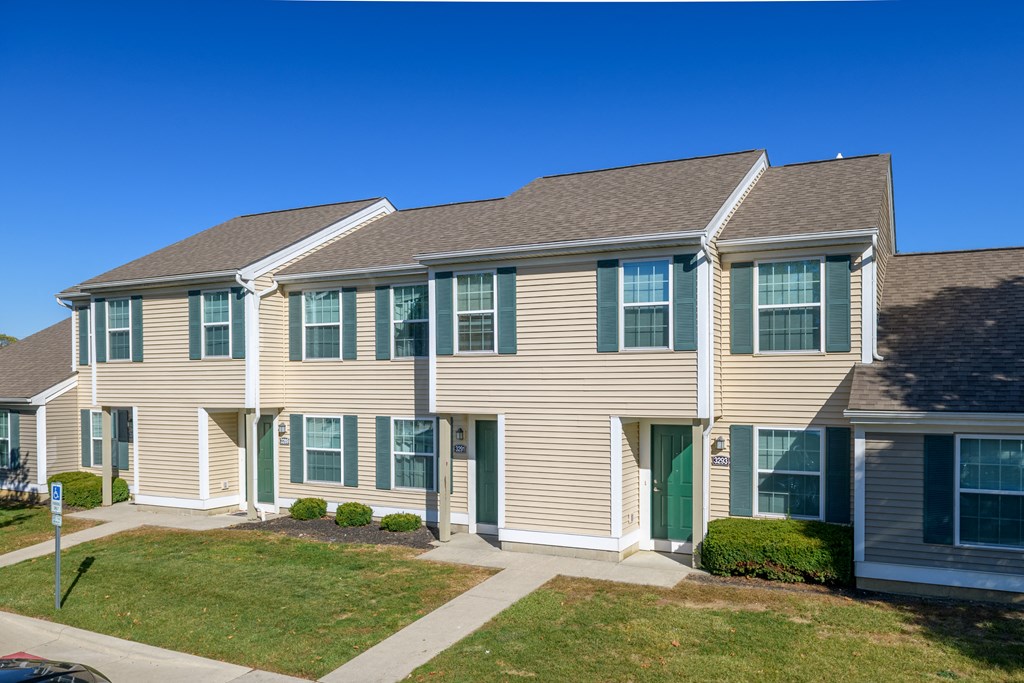 a row of town homes with tan siding and green doors