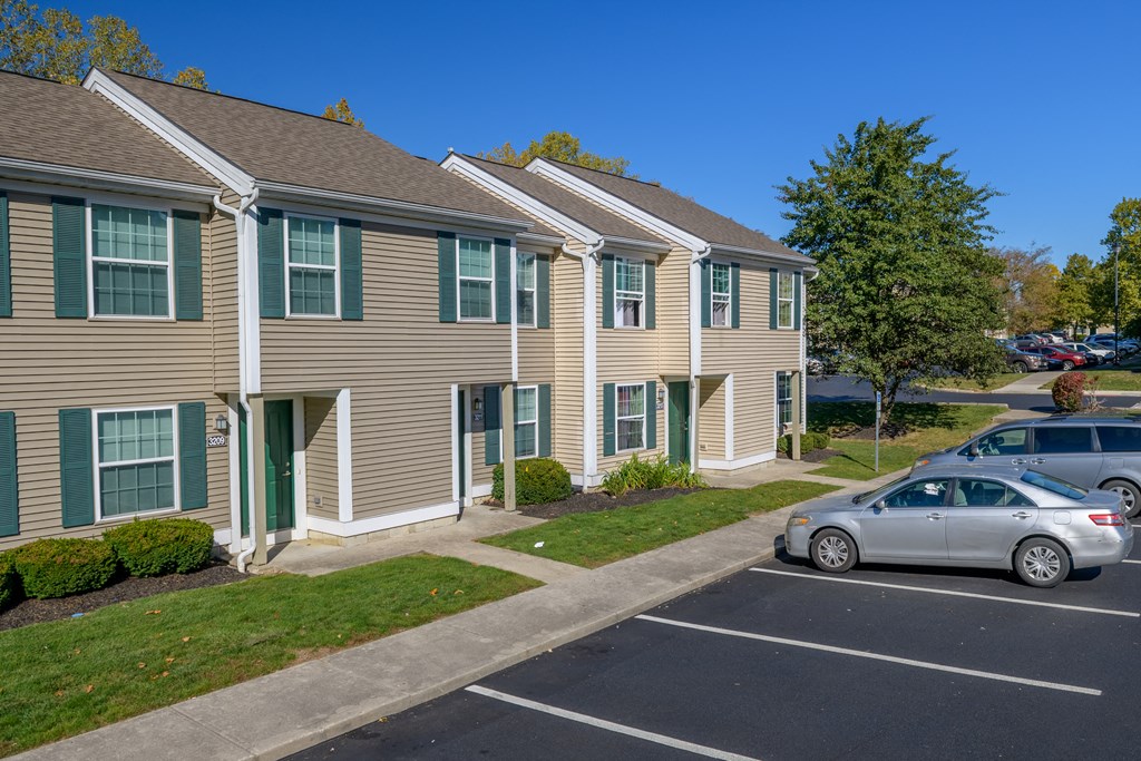 a row of apartment buildings with cars parked in a parking lot